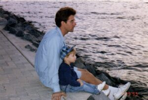 Father and son sitting by the water.