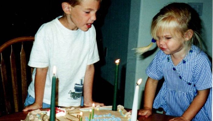 Two children blowing out candles on a birthday cake.