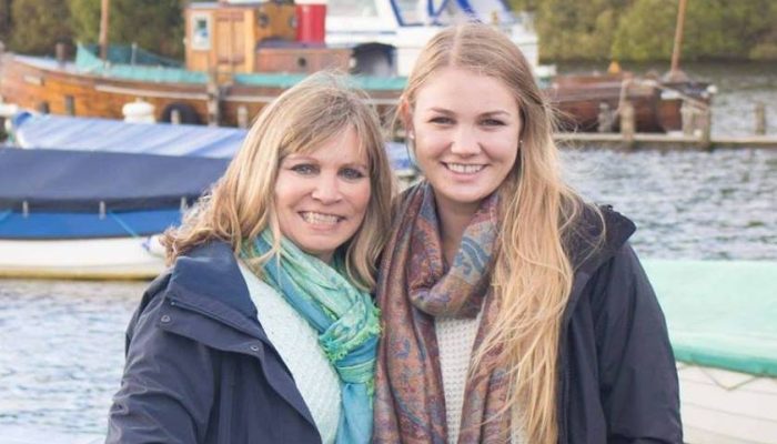 Blonde mother and adult daughter standing side by side with scarfs.