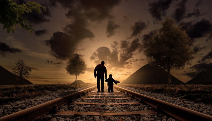 Man walking with child on train tracks